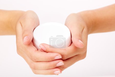 Female manicured hands holding cream