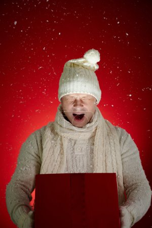 Man in winterwear holding open giftbox