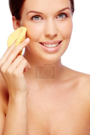 Woman purifying face with sponge