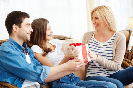 Girl and her father giving present to woman