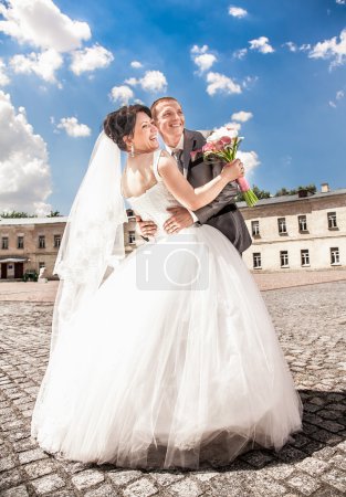Married couple hugging against blue sky on square