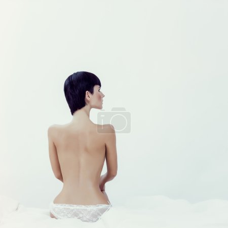 Fashion portrait of a beautiful girl in white bed