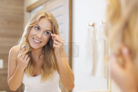 Woman tweezing eyebrows