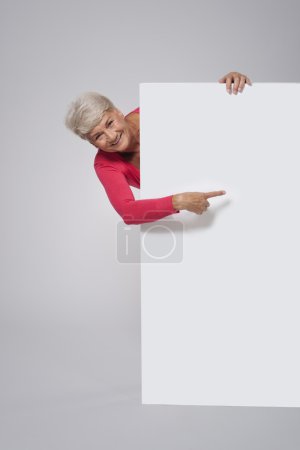 Senior woman showing on empty whiteboar