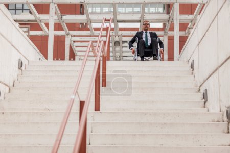 Businessman on wheelchair in front of stairs
