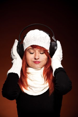 Red hair woman with winter outfit listening to music