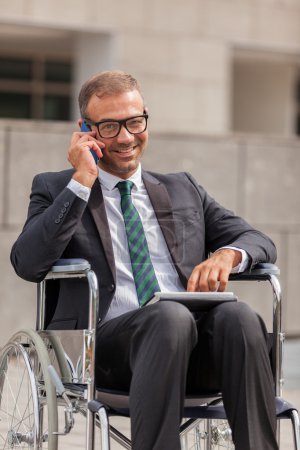 Businessman on wheelchair is phoning