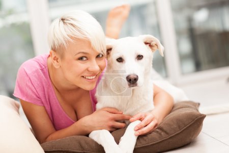 Blonde woman is playing with her dog