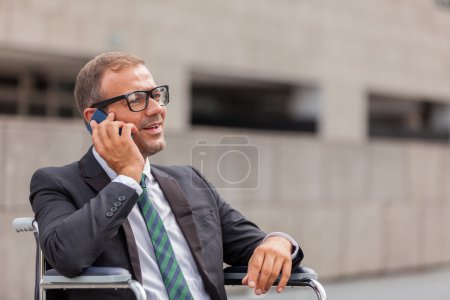 Businessman on wheelchair is phoning