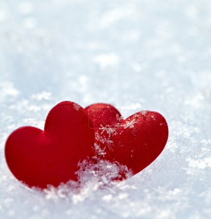 Two red frozen heart on snow