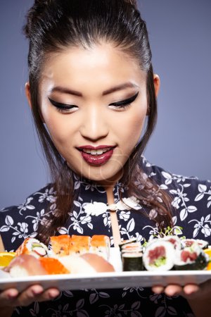 Sushi woman holding sushi with chopsticks looking at the camera