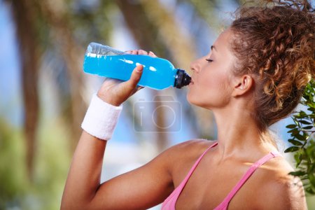Fitness brunette drinking water and cooling off after running