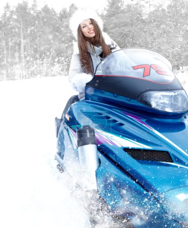 Smiling young woman riding a snowmobile