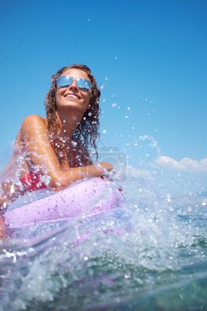 Woman on pink air bed in sea