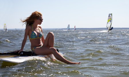 young beautiful woman on windsurfing in water