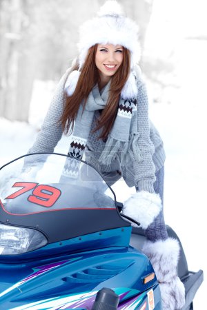 Smiling young woman riding a snowmobile