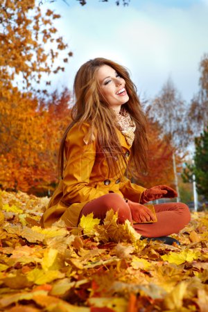Young woman with autumn leaves in hand and fall yellow maple gar