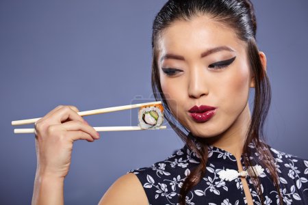 Woman holding sushi with chopsticks