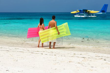 Couple with inflatable rafts looking at seaplane on beach
