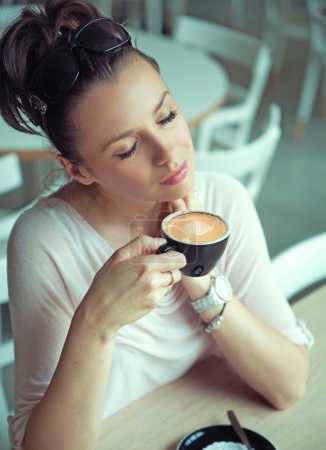 Dreaming brunette lady with cup of coffee
