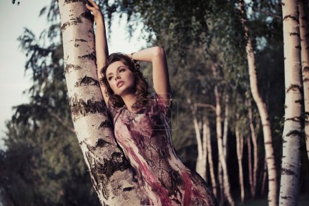An attractive girl leaning on the birch