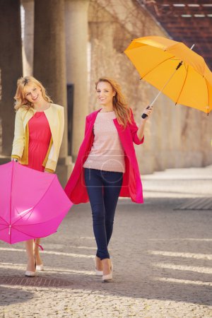 Two attractive girlfreinds with the umbrellas