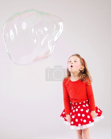 Little girl making the soap bubbles