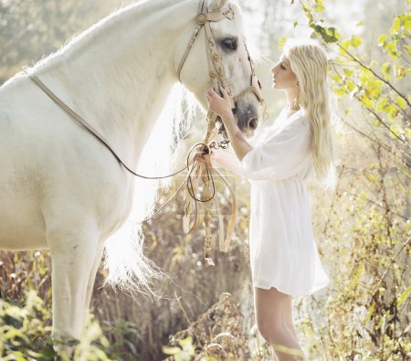 Blonde beautiful woman touching mejestic horse