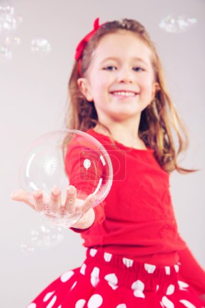 Little girl making large soap bubbles
