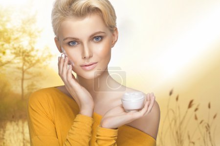 Portrait of young woman applying moisturizer cream on her pretty