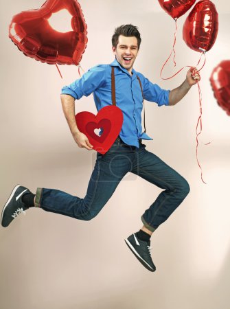 Laughing and jumping man with valentine's balloons
