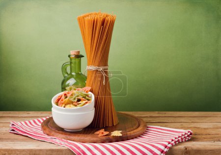 Whole wheat spaghetti and farfalle pasta on wooden table.