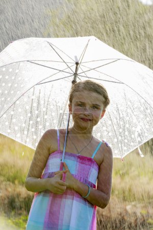 Summer rain - happy girl with an umbrella in the rain