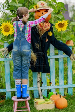Scarecrow and happy girl in the garden