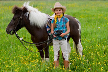 Horse and jockey - little girl is grazing the horse on the meadow
