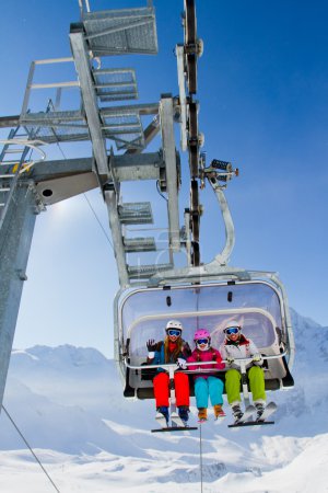 Ski lift, skiing, ski resort - happy skiers on ski lift