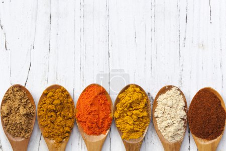 Spices on Wooden Spoons over Distressed White Timber