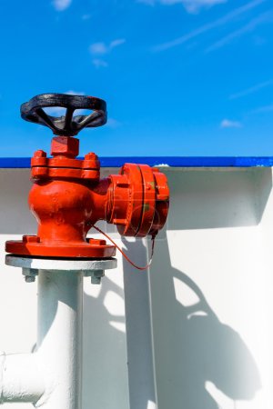Red water or fuel valve against blue sky background.