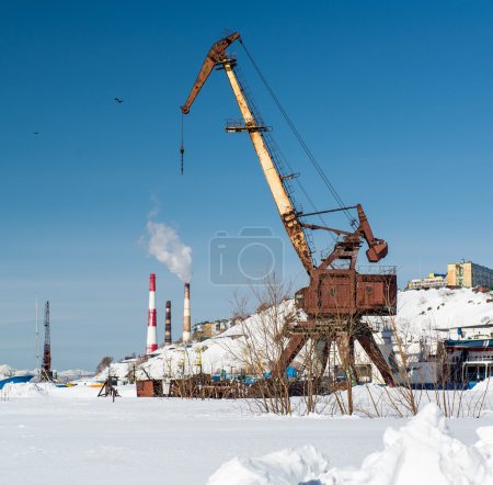 Old crane on Ship graveyard and power plants on a background.