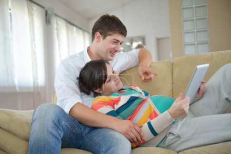 Pregnant couple at home using tablet computer