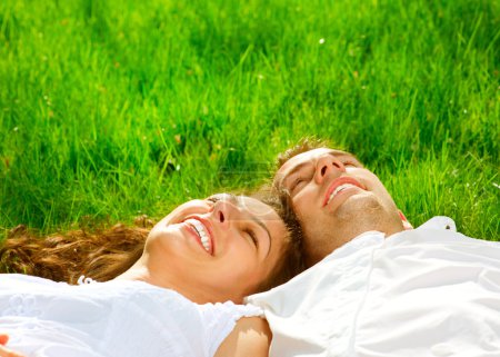 Happy Smiling Couple Relaxing on Green Grass. Park