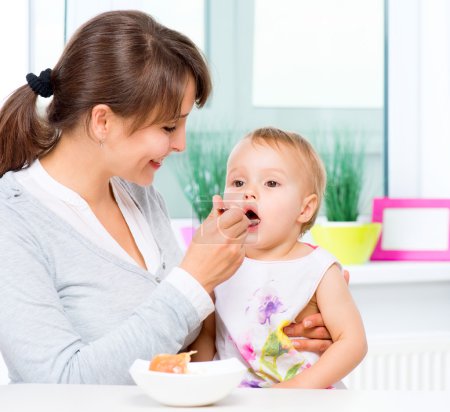 Mother Feeding Her Baby Girl with a Spoon