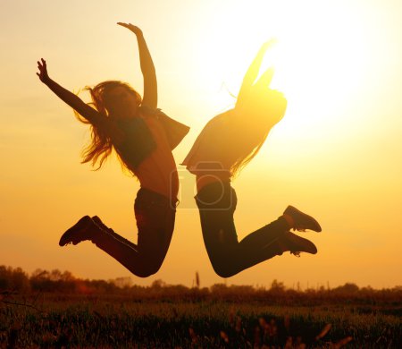 Silhouette of a  girls jumping over sunset
