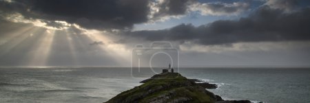 Landscape panorama of Mumbles lighthouse in Wales with sunbeams 