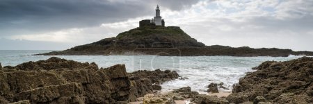 Landscape panorama of Mumbles lighthouse in Wales with sunbeams 