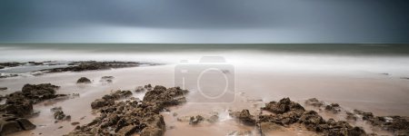 Landscape panorama long exposure image of rocks and sandy beach