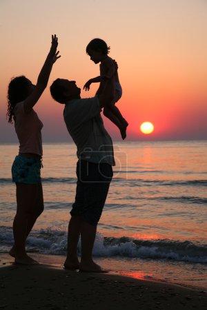 Mummy with daughter and grandfather on sunset at sea