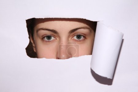 Woman looks in the hole of the sheet of paper