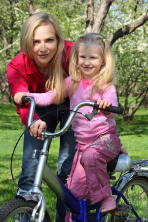 Mother with daughter on bicycle in spring garden