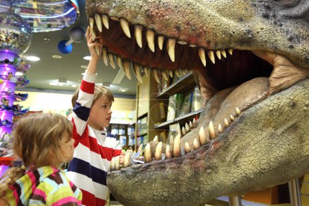 Little boy and girl looking in tyrannosaurus opened mouth focus